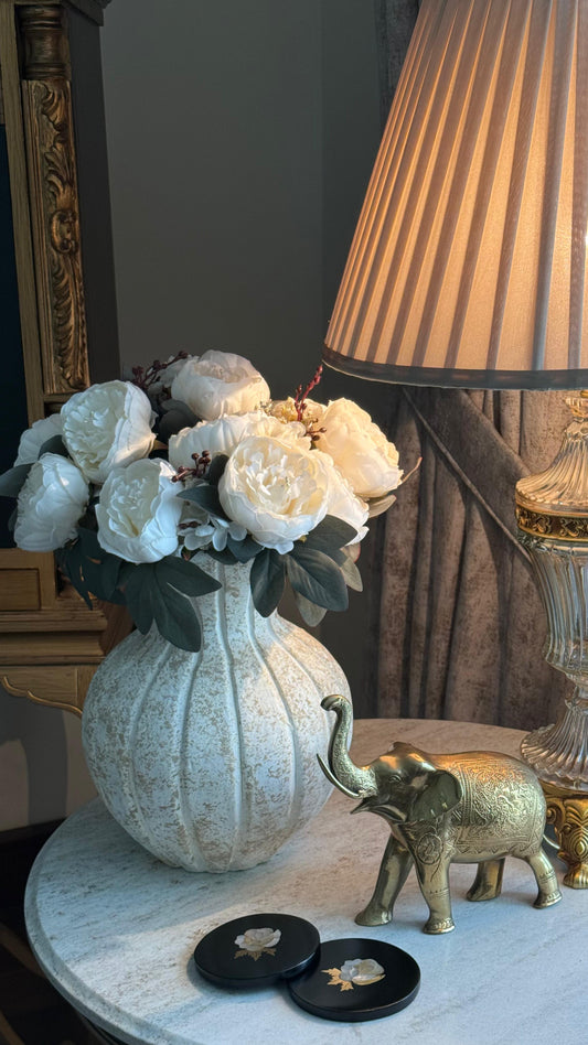 Decorative table setting with a vase of flowers, lamp, and small elephant figurine.